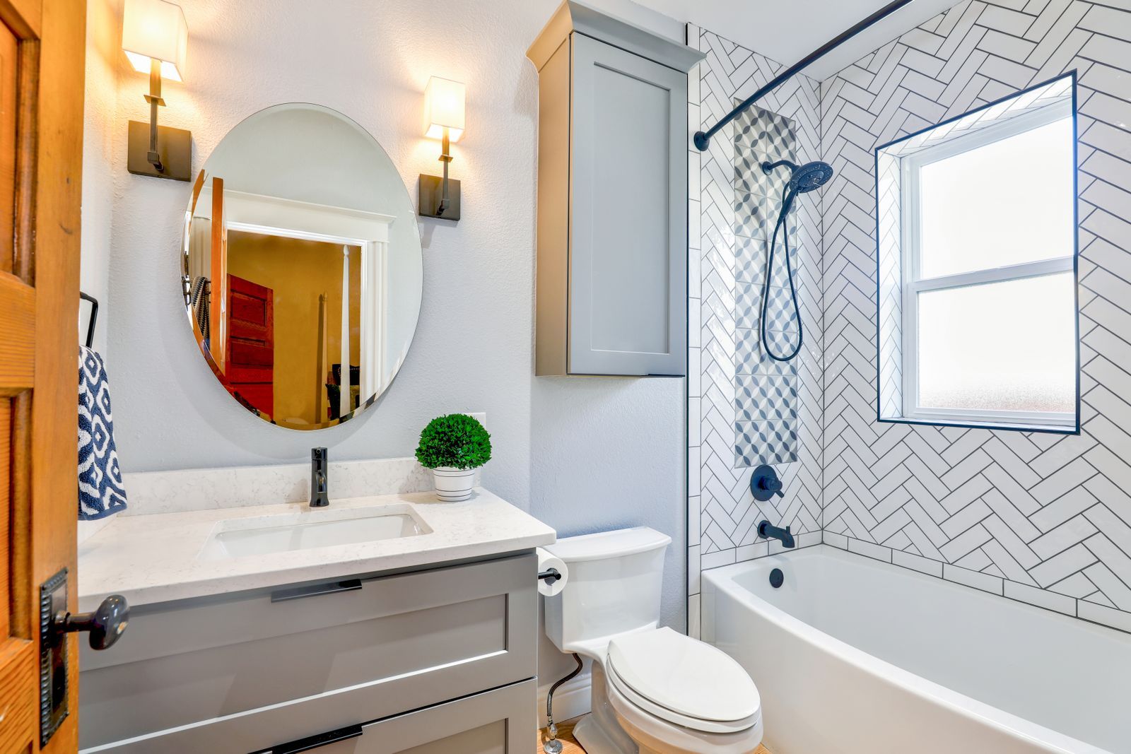 Grey shaker vanity with a round mirror and brass sconces